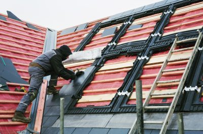 A roofer replacing the tiles on a house roof. ,Construction Site,England A roofer replacing the tiles on a house roof. ,Construction Site,England