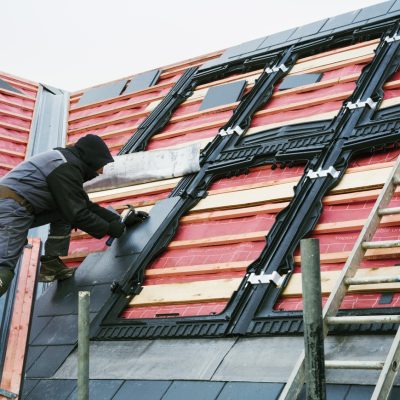 A roofer replacing the tiles on a house roof. ,Construction Site,England